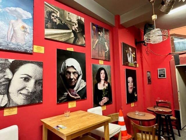 Wand mit gerahmten Arbeiten über den Tischen im Kunst- und Kulturclub Die Winzer